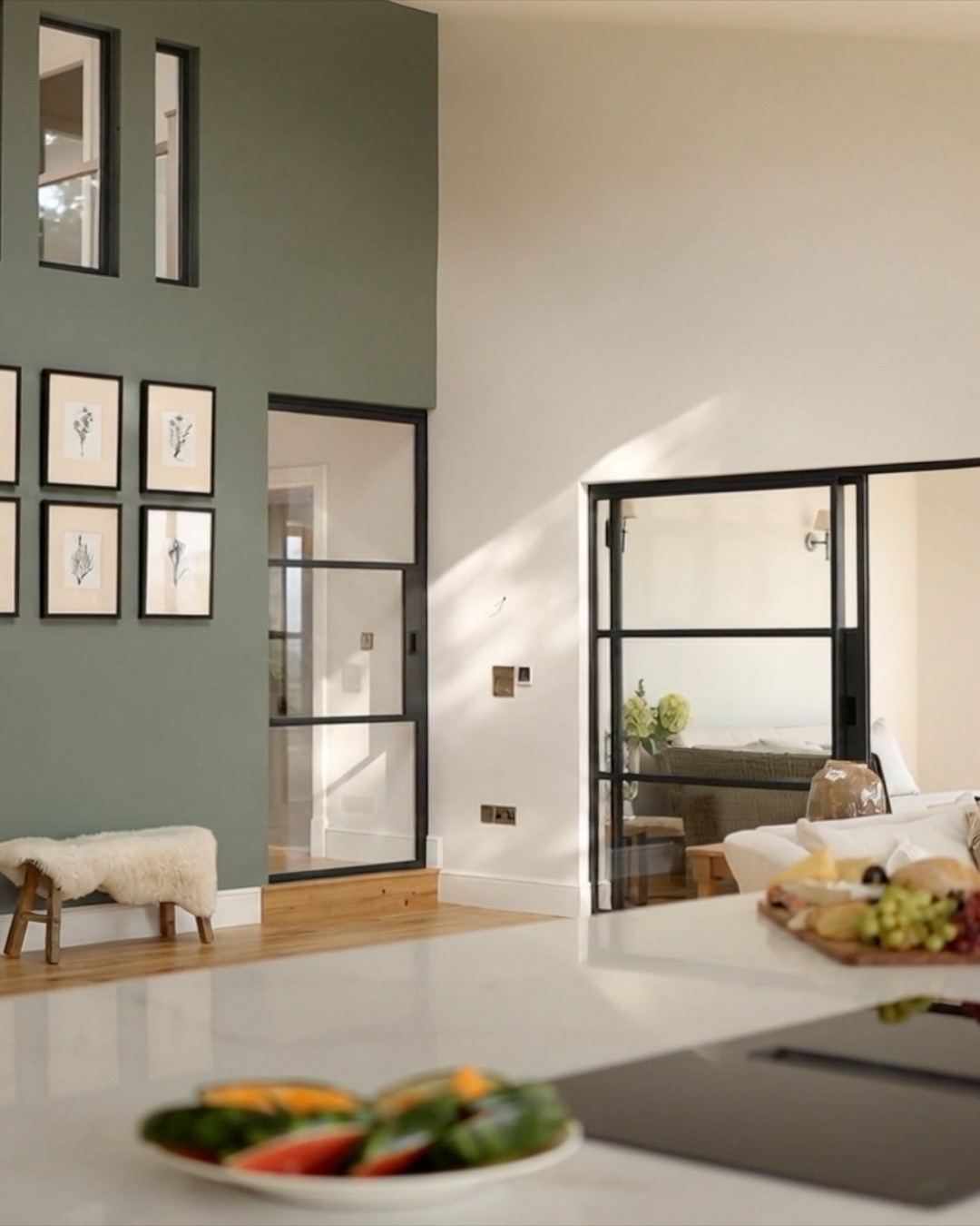 Sunlight crossing a sage-walled interior with glazed doorways